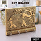 Close-up of the polished gold elephant head and hooks on the wooden key holder.