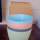 A set of five plastic flower pots with trays displayed on a shelf.