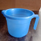 Plastic bath mug in use with water pouring from ergonomic spout