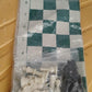 Portable chess set in use outdoors featuring foldable vinyl board and plastic pieces