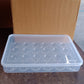 Close-up of a single egg inside clear plastic storage box