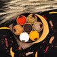 A round plastic masala spice box with seven compartments and a clear lid, showcasing vibrant spices.