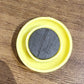 Yellow circular magnet placed next to pen for size reference