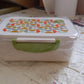 Complete view of the 3 compartment lunch box with its integrated spoon and secure clasps.