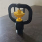 Rotating irrigation sprinkler nozzle actively spraying water in a garden bed.