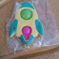Rocket fidget keychain toy next to measuring tape showing dimensions