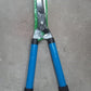 Adjustable hedge shear with sturdy handles for versatile trimming.