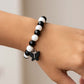 Fashionable bracelet showcasing black and white beads with cross pendant