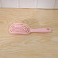 Woman brushing her hair with pink curved styling brush