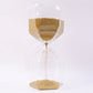 Close-up of yellow sand flowing in glass hourglass timer