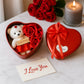 Side view of heart shaped gift box with teddy bear and rose arrangement