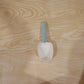 A white plastic measuring spoon demonstrating its use as a bag clip on a food bag.