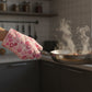 Hand using a heat-resistant oven mitt to safely handle a hot baking dish.