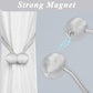 A pair of elegant silver magnetic curtain tiebacks arranged decoratively.