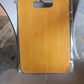 Wooden chopping board hanging on hook by finger hole in neat kitchen setup