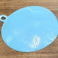 Kitchen setting featuring blue silicone dish scrubber for cleaning