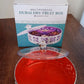 Round silver dry fruit box displayed for home serving on a table.