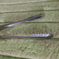 Stainless steel tongs resting on a rustic wooden surface, highlighting versatility.