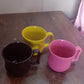 An empty plastic coffee mug ready for use, showcasing its sturdy base and comfortable grip.