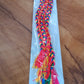 Braided hair extension hanging on display showing vibrant colors and tassels
