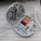 Close-up of small sewing tools like a needle threader, pins, and thimble from the kit.