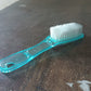 Plastic scrubbing brush featuring an ergonomic handle design.