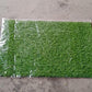 Display of the soft and durable 58x38cm plastic grass, suitable for indoor and outdoor use.