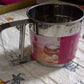 Detailed view of the handheld flour sifter, showcasing its fine mesh screen.