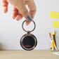 Elegant round shape metal keychain with chrome frame and black center.