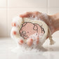 Side view of a cartoon bath scrubber sponge with a secure hanging rope.