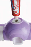 White automatic toothpaste dispenser and 4-slot toothbrush holder mounted on a wall.